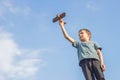 Little boy plays with toy wooden plane. Happy kid playing with toy wooden airplane against sky background Royalty Free Stock Photo