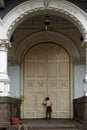 Little boy poking through huge wooden door