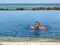 A little boy in the pool swims in armlets and lets out a jet of water from his mouth Royalty Free Stock Photo