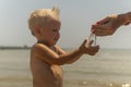 Little boy pour sand in his hands on the shore of the sea