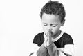 Little boy praying with his hands clenched together