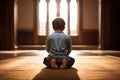 A little boy praying on his knees indoors in the sunlight, AI generation