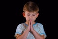 The little boy prays to God with his hands bent. Close-up on a black background Royalty Free Stock Photo