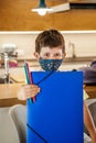 Little boy with a protective mask and school supplies at home ready for school. Vertical