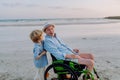 Little boy pushing his granfather on wheelchair, enjoying sea together. Royalty Free Stock Photo