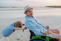Little boy pushing his granfather on wheelchair, enjoying sea together. Royalty Free Stock Photo
