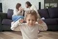 Little boy puts fingers in ears, parents fighting at background