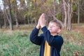 A little boy raises his hands to God in prayer in nature in the park