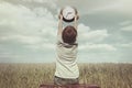 Little boy raises in the sky a watch in a surreal landscape