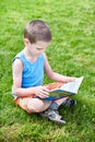 Little boy reading book outdoori on grass Royalty Free Stock Photo