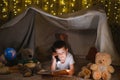 Little boy reading book in play tent at night Royalty Free Stock Photo