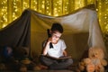 Little boy reading book in play tent at night Royalty Free Stock Photo