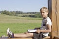 Little boy reading book at summer terrace. Casual clothes. Nature background. People, education, knowledge concept Royalty Free Stock Photo