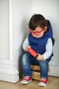 Little boy in red with glasses sitting on a bunch