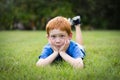 Little boy with red hair lying in the grass