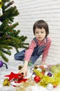 Little boy in red plaid shirt and denim overalls decorates a Christmas tree Royalty Free Stock Photo