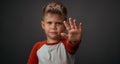 Little boy in red shirt unhappy showing stop with his hand isolated on grey background. Human emotions, facial Royalty Free Stock Photo