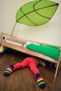 Little boy in red striped trousers and socks looking under the bed. Toy under the bed.