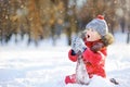 Little boy in red winter clothes having fun with snow