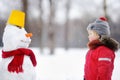 Little boy in red winter clothes having fun with snowman Royalty Free Stock Photo