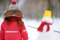 Little boy in red winter clothes having fun with snowman in snowy park Royalty Free Stock Photo