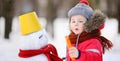 Little boy in red winter clothes having fun with snowman in snowy park Royalty Free Stock Photo