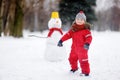 Little boy in red winter clothes having fun with snowman Royalty Free Stock Photo