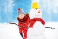 Little boy in red winter clothes having fun with snowman in snowy park Royalty Free Stock Photo
