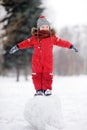 Little boy in red winter clothes having fun with snowman Royalty Free Stock Photo