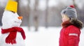 Little boy in red winter clothes having fun with snowman Royalty Free Stock Photo