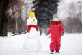 Little boy in red winter clothes having fun with snowman in winter park Royalty Free Stock Photo