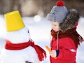 Little boy in red winter clothes having fun with snowman in snow Royalty Free Stock Photo