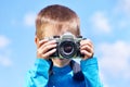 Little boy with retro SLR camera on blue sky Royalty Free Stock Photo