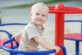 Little boy rides on carousel swing. Toddler plays on playground in summer. Concept of kindergarten