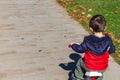 Little Boy Rides His Tricycle Away on a Sidewalk Royalty Free Stock Photo