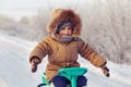 Little boy riding his kids snowmobile winter snow-covered road