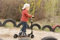 Little boy riding his scooter on a dirt lane Royalty Free Stock Photo