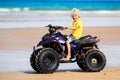 Child on quad bike at beach. All-terrain vehicle. Royalty Free Stock Photo