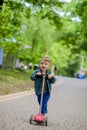 Little boy riding scooter in city park in aummer. Kids sports outdoors. Happy child playing with his scooter. Kid learn to ride Royalty Free Stock Photo