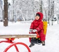 Little boy riding on swing in winter