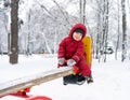 Little boy riding on swing in winter