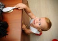 Little boy risking accident with falling furniture. Royalty Free Stock Photo