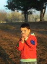 A little boy in rubber boots walks through the forest and holds a magnifying glass in his hands, examines the stones, a mineral. Royalty Free Stock Photo