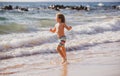 Little boy running on beach shore splashing water in blue sea. Kid walking the summer beach. Royalty Free Stock Photo