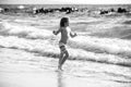 Little boy running on beach shore splashing water in blue sea. Kid walking the summer beach. Royalty Free Stock Photo