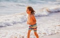 Little boy running on beach shore splashing water in blue sea. Kid walking the summer beach. Royalty Free Stock Photo