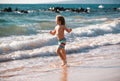 Little boy running on beach shore splashing water in blue sea. Kid walking the summer beach. Royalty Free Stock Photo