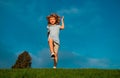 Little boy running and jumping on the grass near a spring green meadow on blue sky. Happy child girl playing on sunny Royalty Free Stock Photo