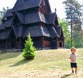 Little boy running and playing in front of the Gol Church, a stave church originally built in Gol city, now in Oslo. Royalty Free Stock Photo