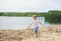 Little boy running on a sand near a pond Royalty Free Stock Photo